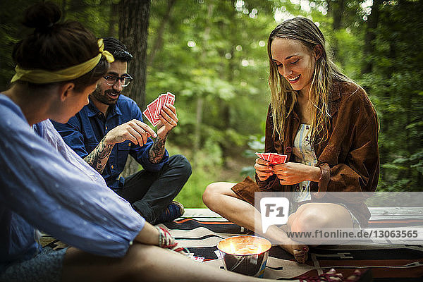 Freunde spielen Kartenspiel  während sie auf einer Veranda im Wald sitzen