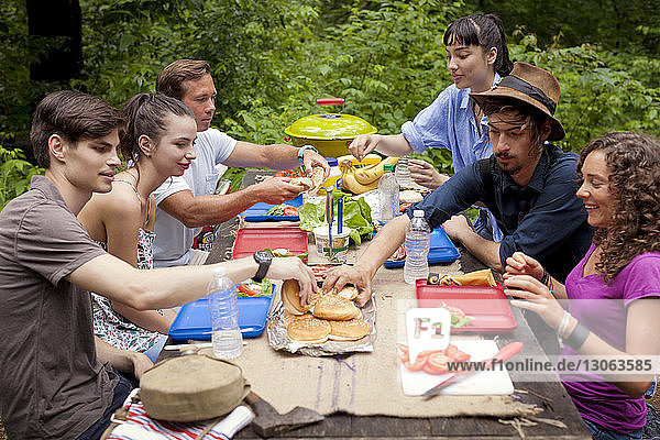 Freunde beim Frühstücken am Picknicktisch im Wald