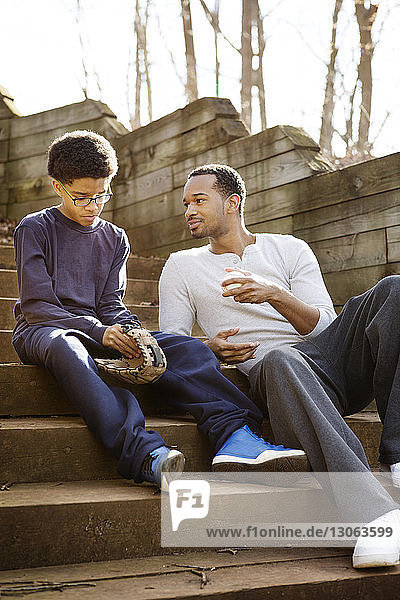 Vater sieht den Sohn an  der einen Baseballhandschuh hält  während er auf einer Treppe sitzt