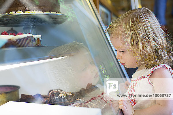 Kleines Mädchen betrachtet süße Lebensmittel  die im Laden ausgestellt sind