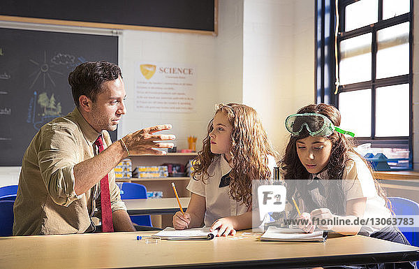 Lehrerin erklärt Schülerinnen im Labor ein wissenschaftliches Experiment