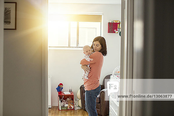 Mother looking at daughter while standing at home on sunny day
