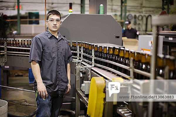 Portrait of man standing by bottling plant at brewery