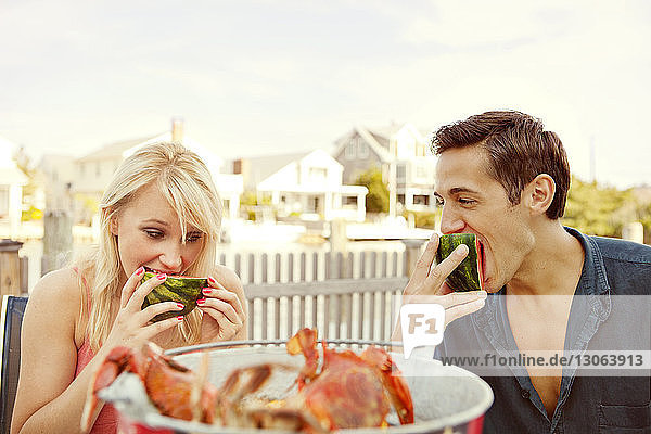 Paar isst Wassermelone  während es im Hinterhof sitzt