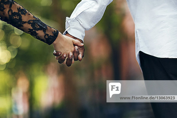 Ausgeschnittenes Bild eines jungen Paares  das auf der Straße Händchen hält