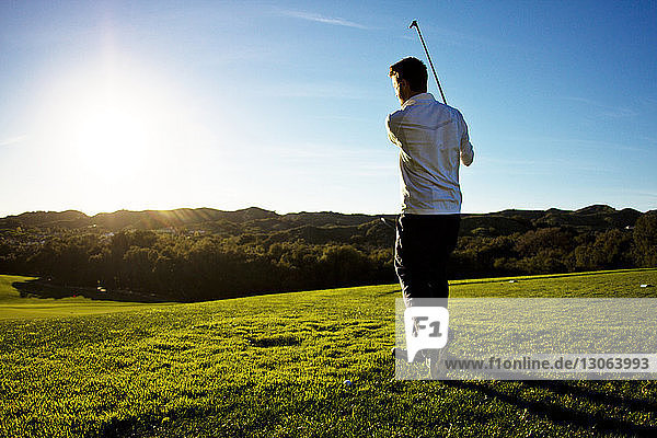 Rear view of man playing golf against clear sky