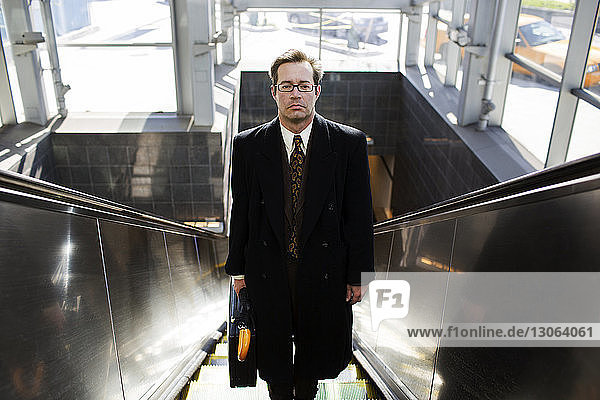Porträt eines auf der Rolltreppe stehenden Geschäftsmannes