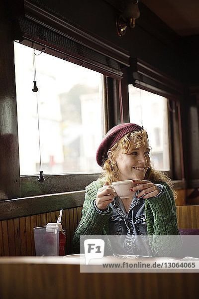 Frau mit Kaffeetasse schaut weg  während sie im Restaurant sitzt