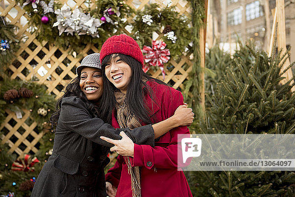 Cheerful woman embracing friend at Christmas market