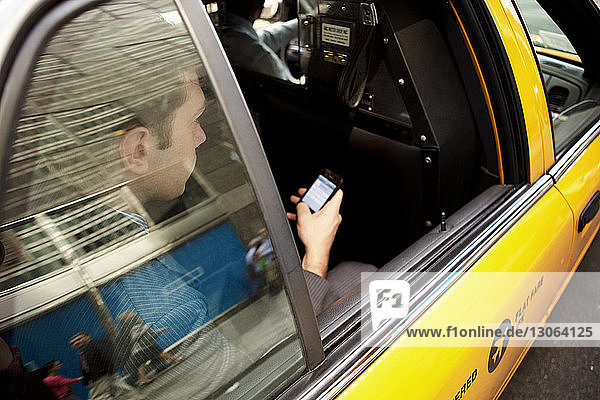Geschäftsmann benutzt Smartphone während einer Taxifahrt