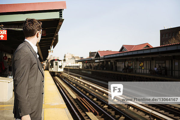 Side view of businessman waiting for train at railroad platform