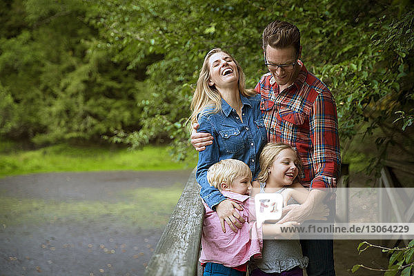 Happy family leaning on railing against plants in yard