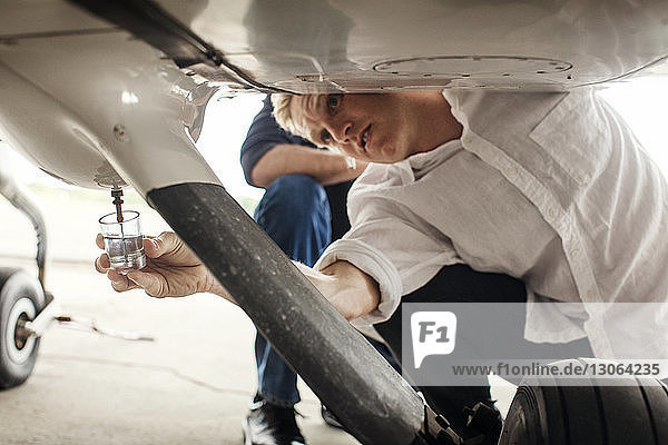 Mechaniker reparieren Propellerflugzeug in der Hocke auf dem Flugplatz