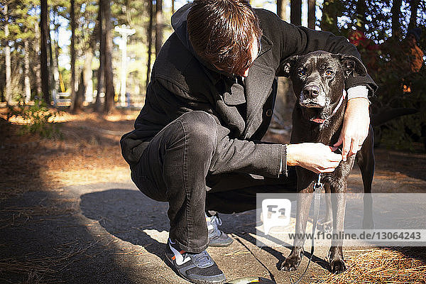 Mann bindet im Wald Haustierleine an Hund