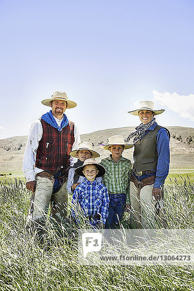 Portrait of cowboy family standing on grassy field