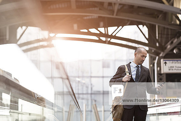 Mann benutzt Mobiltelefon  während er auf der Rolltreppe in der U-Bahn-Station steht