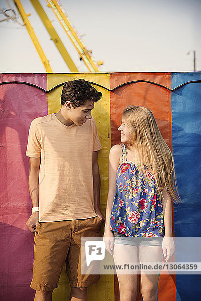 Glückliches Paar steht vor mehrfarbiger Metallwand im Vergnügungspark