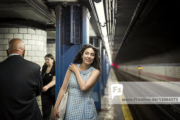 Lächelnde Frau wartet in der U-Bahn auf den Zug