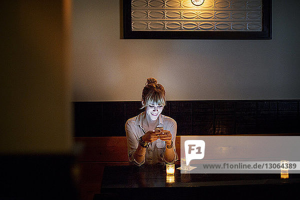 Frau benutzt Telefon  während sie in einer Bar sitzt