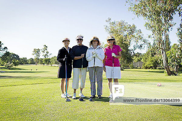 Portrait of happy friends standing at golf course