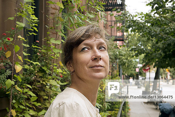 Frau schaut weg  während sie gegen Gebäude in der Stadt steht