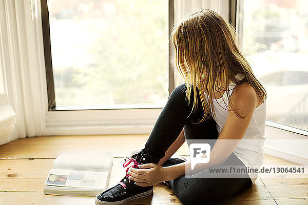 Girl studying while sitting by window at home