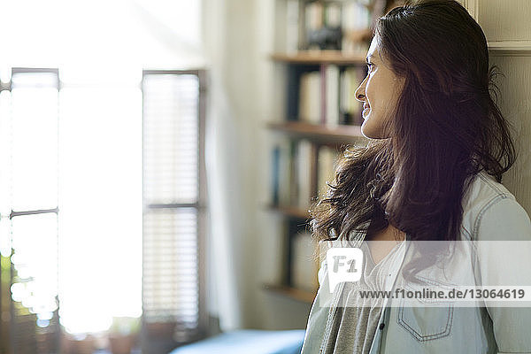 Woman looking away while leaning on door at home