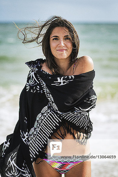 Portrait of woman wrapped in sarong standing at beach