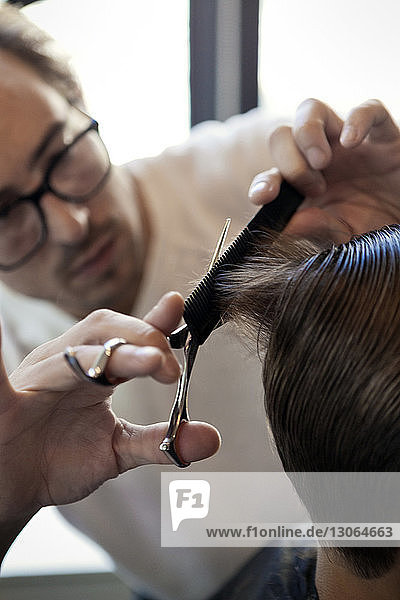 Friseur schneidet jungen Mann die Haare im Salon
