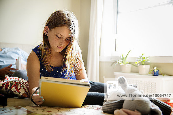 Mädchen benutzt Tablet-Computer  während sie sich zu Hause im Bett entspannt