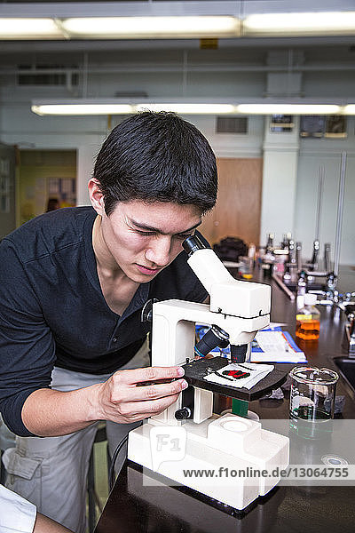 Mann schaut im naturwissenschaftlichen Unterricht durch das Mikroskop