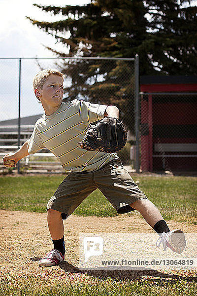 Boy throwing baseball at field