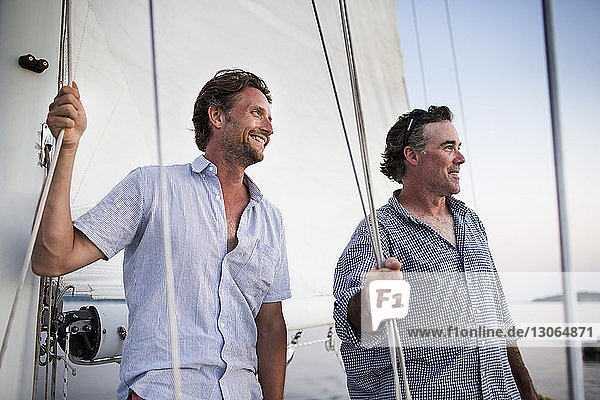 Seitenansicht eines glücklichen Mannes  der ein Seil bindet  während er auf einer Yacht steht