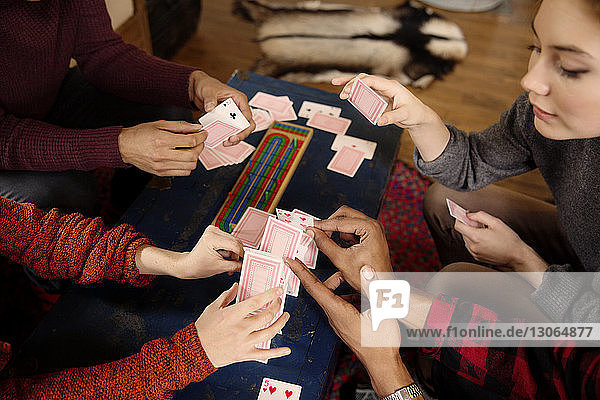 High angle view of friends stacking cards at table