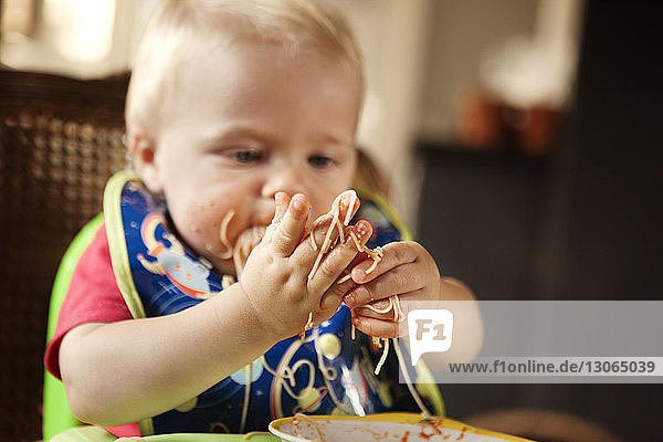 Kleiner Junge schaut beim Essen auf Nudeln