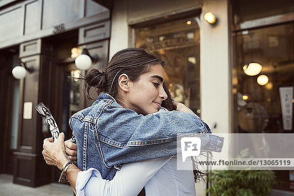 Tochter umarmt Mutter  während sie an Geschäften in der Stadt steht