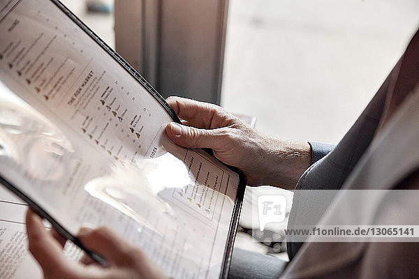 Cropped image of man holding menu while sitting in restaurant