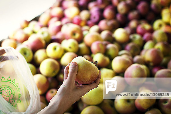 Ausgeschnittenes Bild eines handgehaltenen Apfels am Marktstand