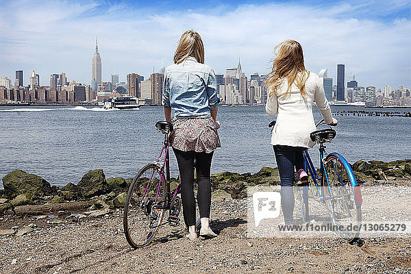 Rückansicht von Freunden mit Fahrrad am Flussufer