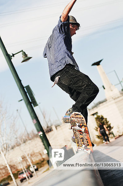 Kippschuss eines Mannes  der an einem sonnigen Tag einen Stunt mit Skateboard macht