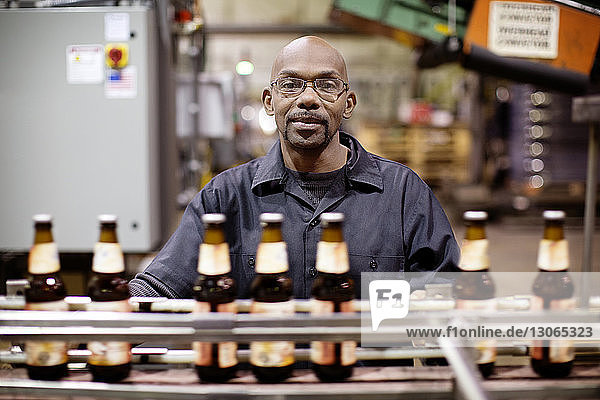 Portrait of worker standing by bottling plant at brewery