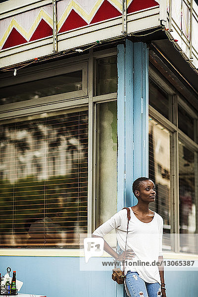 Frau schaut weg  während sie sich an die Wand eines Cafés lehnt
