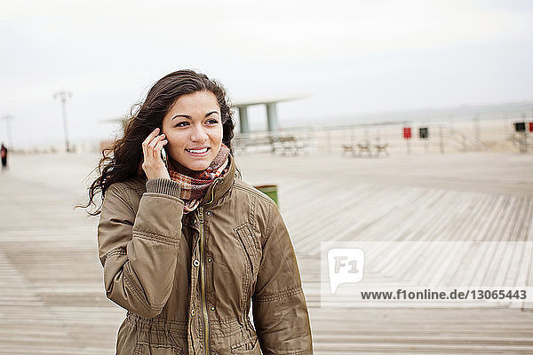 Teenager-Mädchen telefoniert mit dem Handy  während sie gegen den Himmel steht