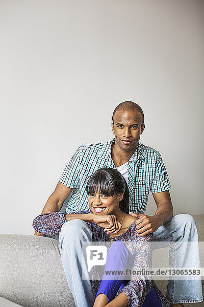Porträt eines lächelnden Paares  das zu Hause auf dem Sofa sitzt