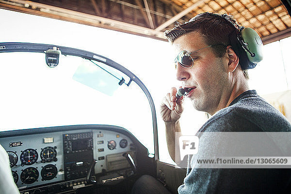 Mechaniker untersucht Kopfhörer  während er im Flugzeug sitzt