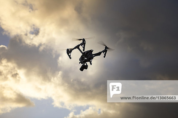 Niedrigwinkelansicht eines Quadcopters  der gegen bewölkten Himmel fliegt