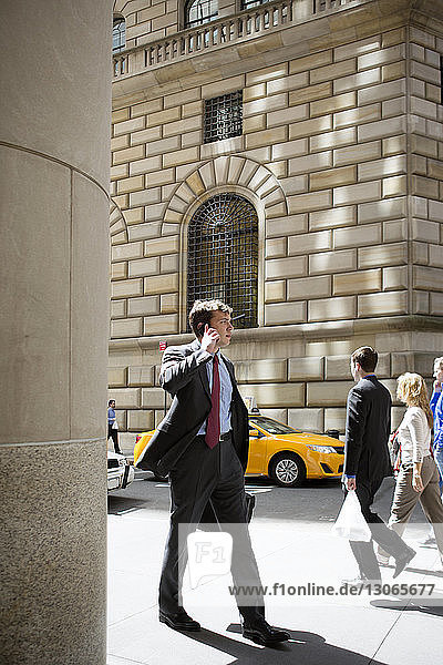 Geschäftsmann spricht mit einem Smartphone  während er in der Stadt auf der Straße geht