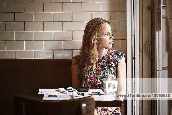 Nachdenkliche Frau schaut weg  während sie im Restaurant sitzt