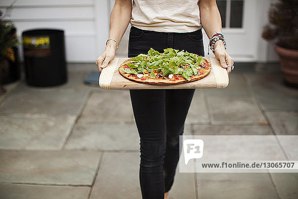 Mitschnitt einer Frau  die beim Gehen im Rasen Pizza trägt