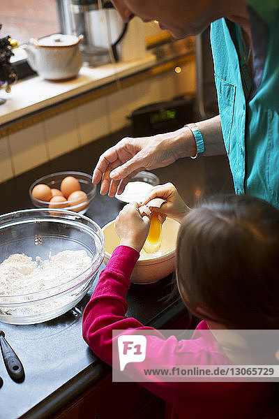 Schrägaufnahme einer Großmutter  die einem Mädchen das Kochen beibringt  während sie zu Hause in der Küche steht